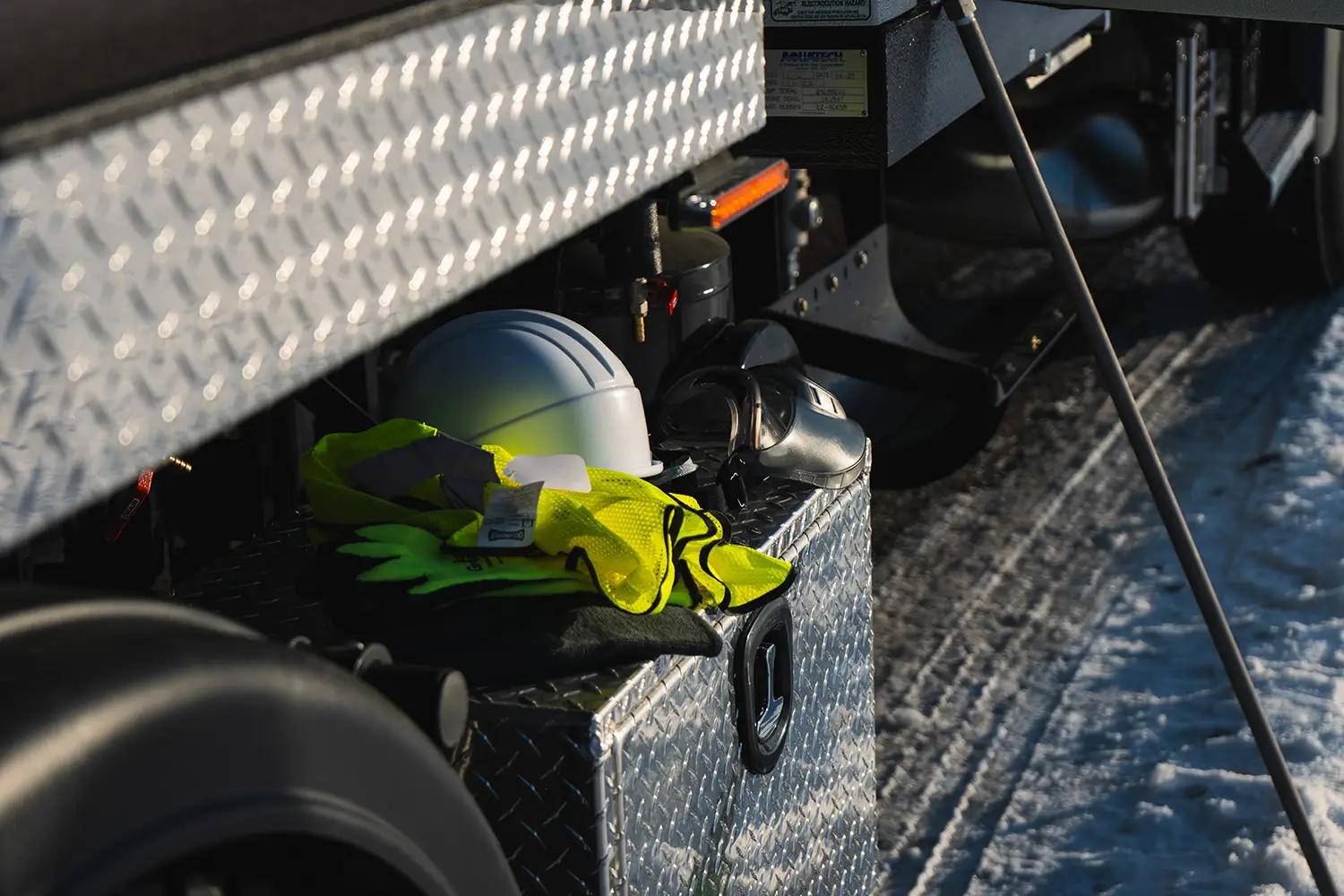 Work boots and a hard hat stowed in a diamond-plate truck bed, ready for field service